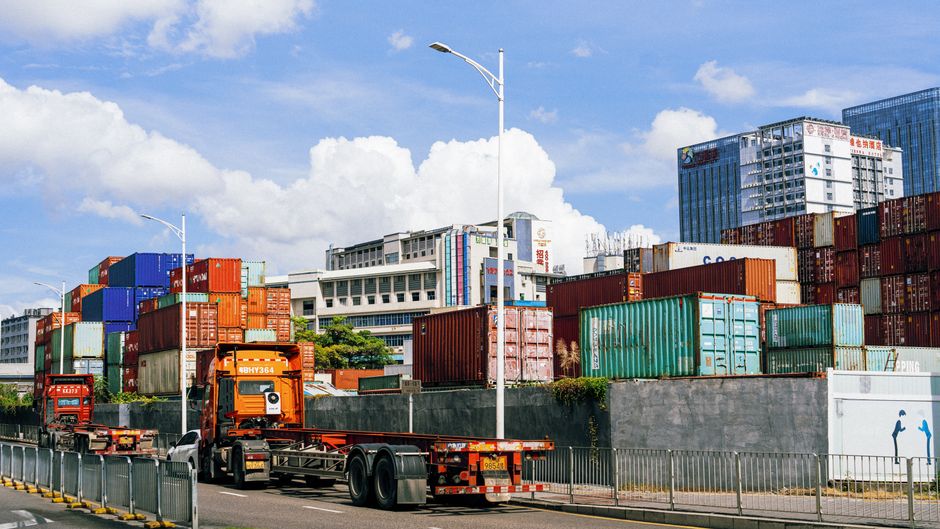 Colorful shipping containers stack at an industrial port under clear skies.